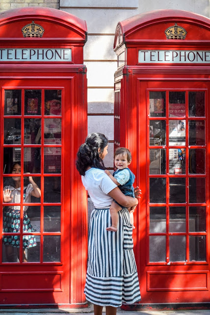 Kids playing in London red telephone booths