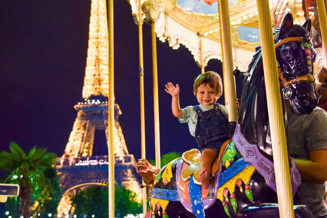  Best Things to Do In Paris With Kids featured by top US family travel blog, Local Passport Family: image of a toddler on a carousel by the Eiffel Tower