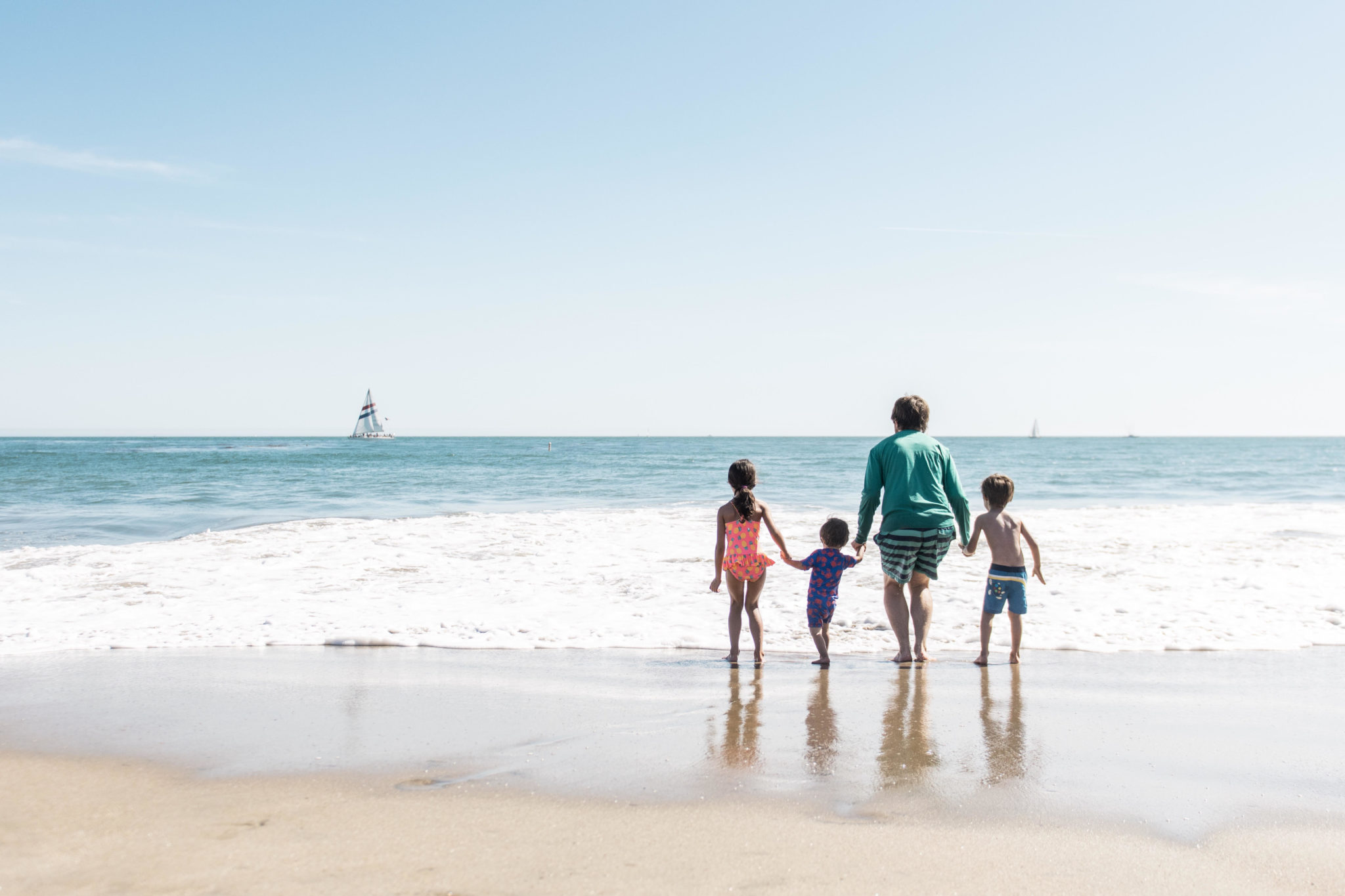 summer goals setting for kids featured by top US family travel blog, Local Passport Family: image of a family running on the beach to get into the waves