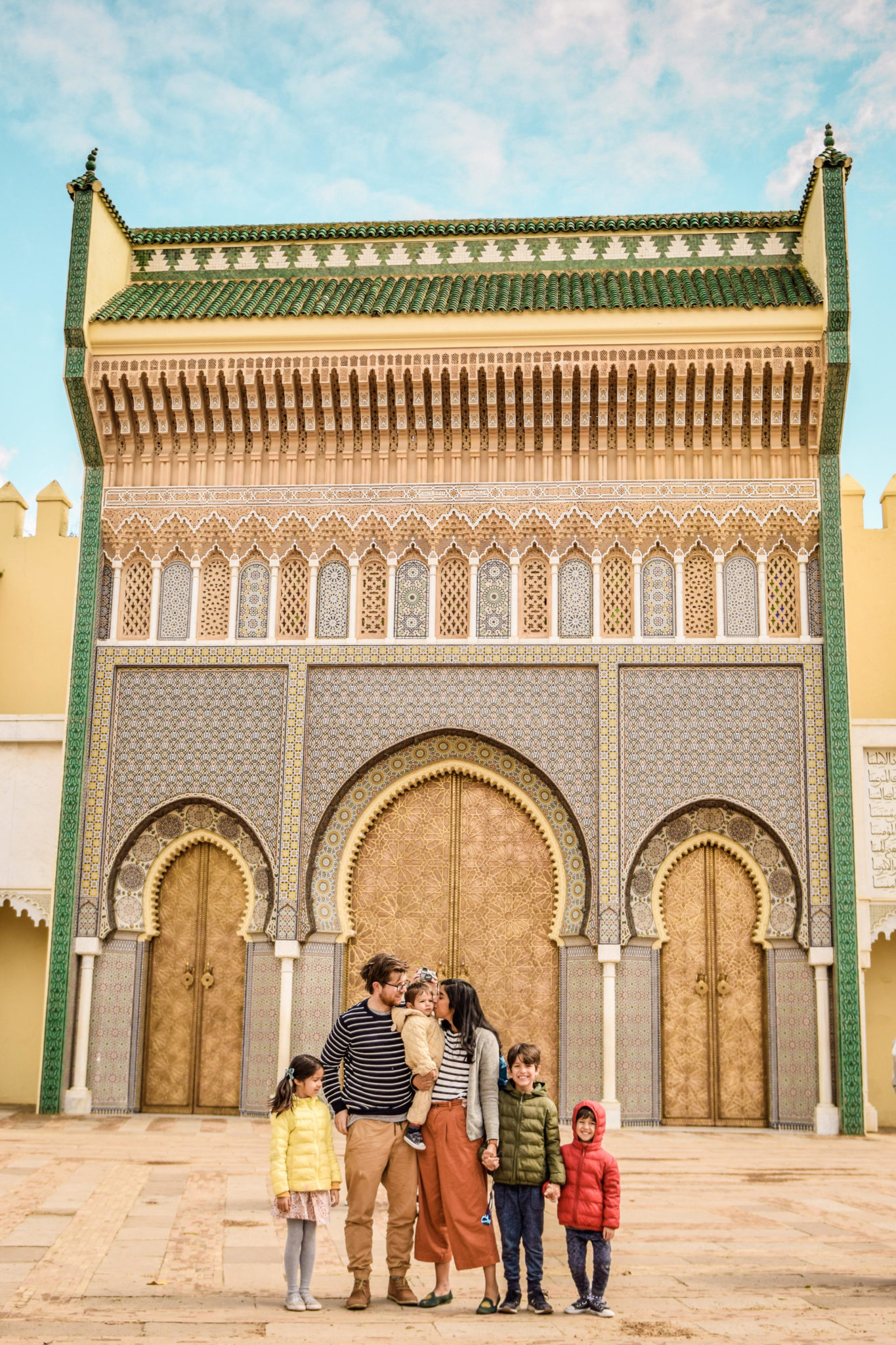 fes morocco family travel | 7 Reasons to Take a Morocco Family Vacation by popular Northern California travel blog, Local Passport Family: image of a family standing outside an ornate building in Morocco. 
