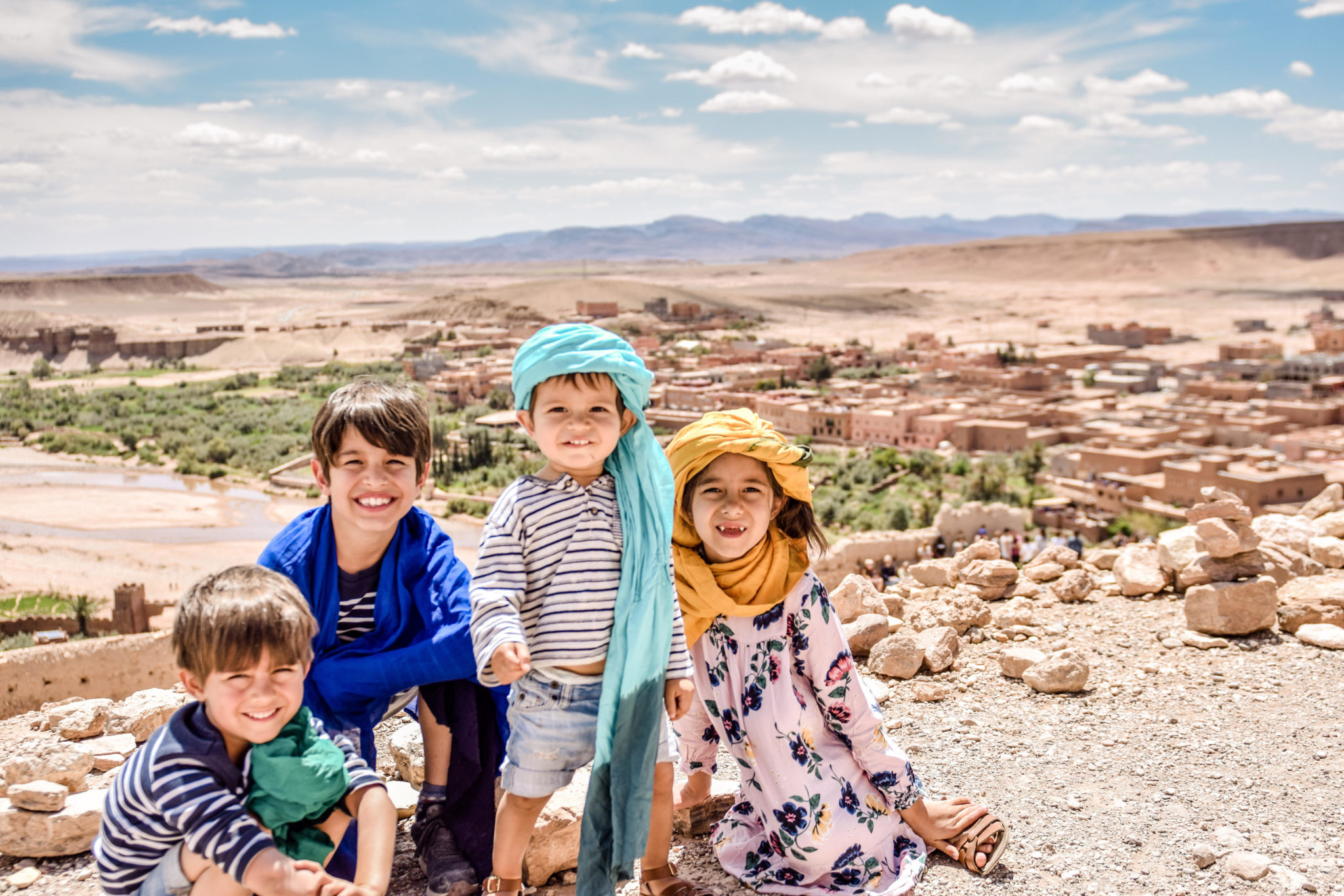 morocco unesco site travel with kids| 7 Reasons to Take a Morocco Family Vacation by popular Northern California travel blog, Local Passport Family: image of a 4 kids sitting outside with a Moroccan city behind them.
